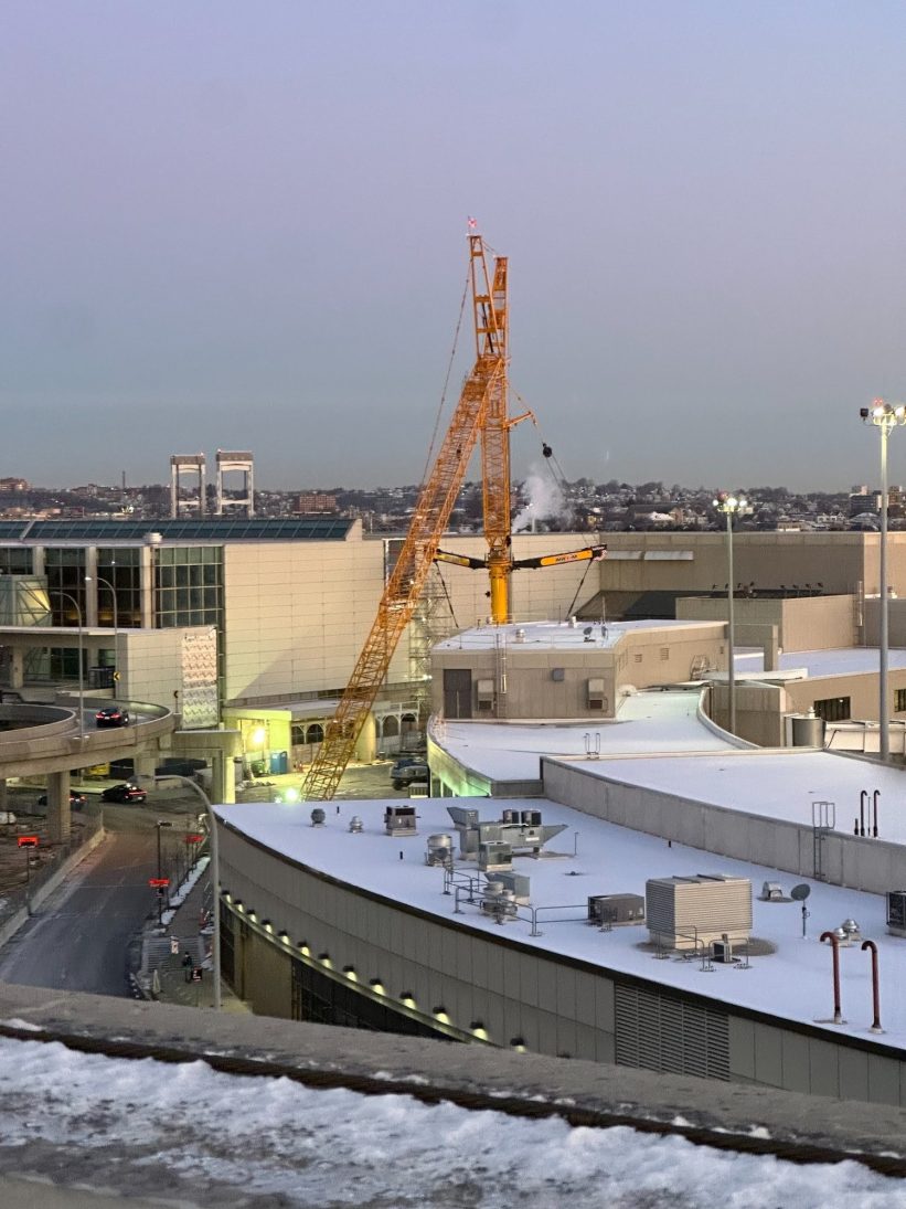 Liebherr LTM 1750 all-terrain crane with luffing jib rigged over Terminal E at snow-covered Boston Logan airport