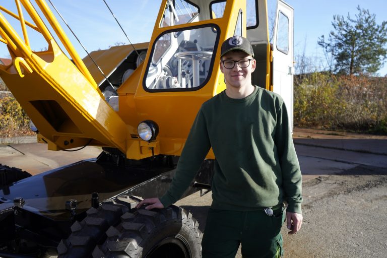 Apprentice Patrick Niemeier beside the restored 1959 Sennebogen S803 duty cycle crane