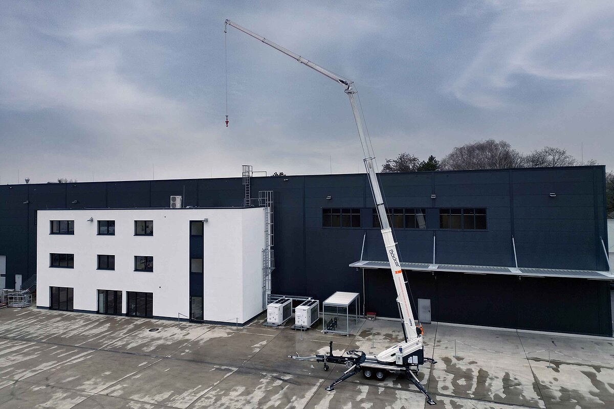 Böcker AHK 36e X trailer crane set up beside an industrial building with the boom extended