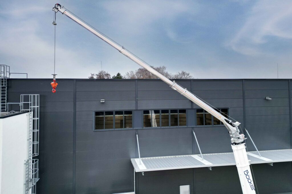 Böcker AHK 36e X lifting material to a roof edge with its fully hydraulic boom