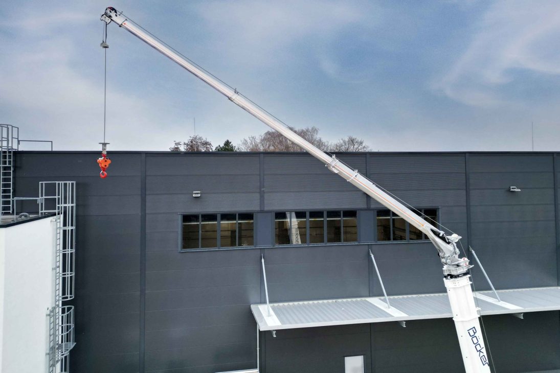 Böcker AHK 36e X lifting material to a roof edge with its fully hydraulic boom