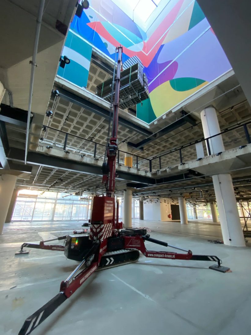 Hoeflon C10e compact crane placing a window pane at a department store façade