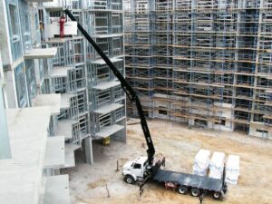 HIAB loader crane on a US flatbed truck lifting building materials into a steel-framed structure