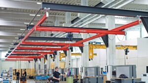 Demag KBK light crane systems with red aluminium girders installed in a production hall