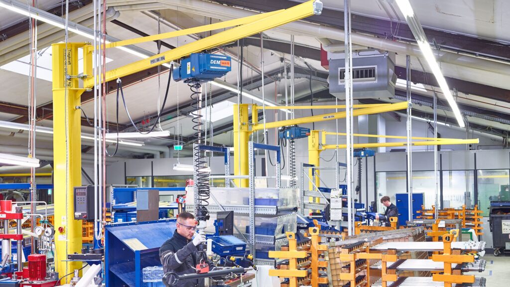 Demag KBK pillar-mounted slewing jib cranes with chain hoists at assembly workstations
