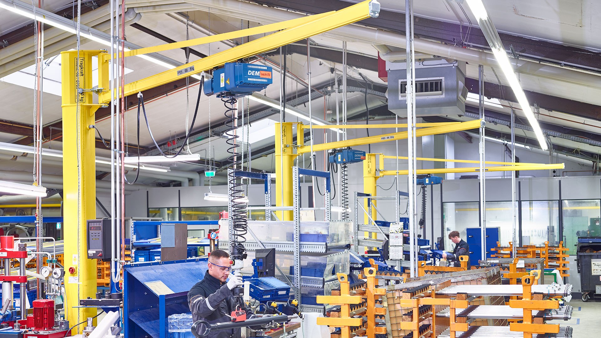 Demag KBK pillar-mounted slewing jib cranes with chain hoists at assembly workstations