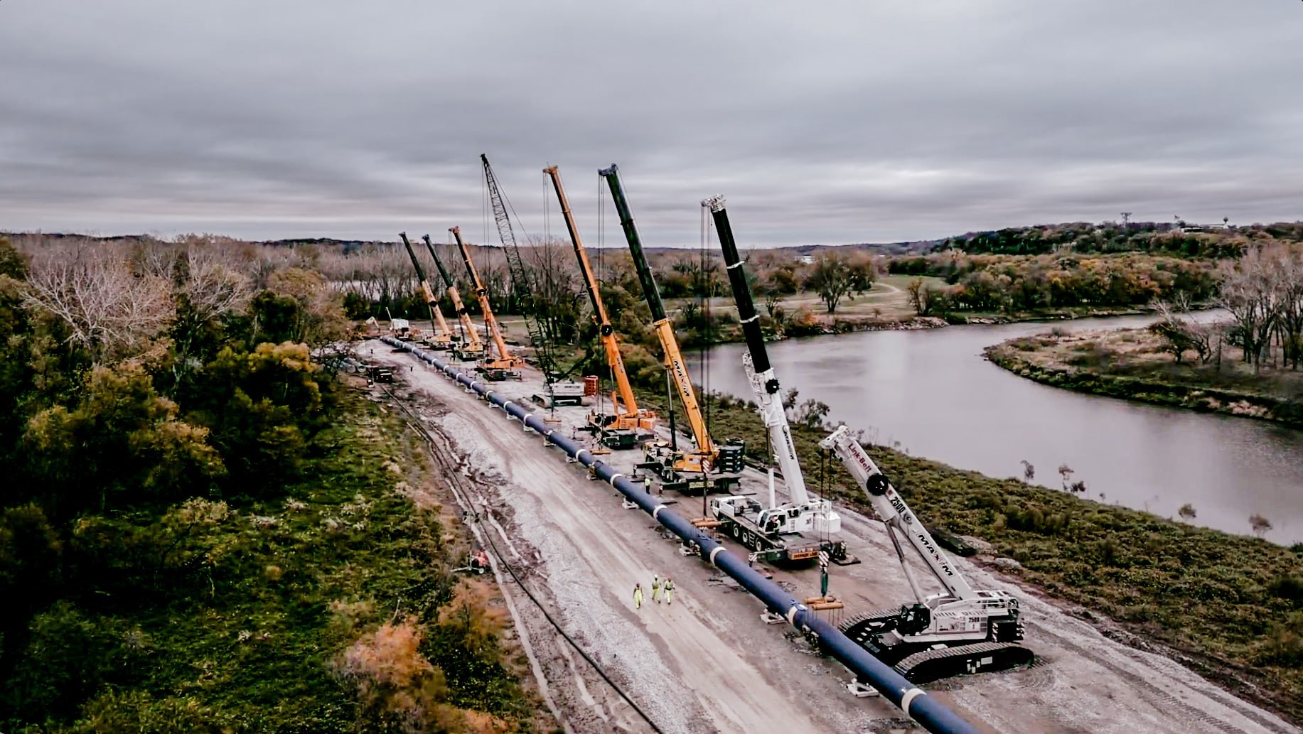 Line of Maxim Crane Works cranes lifting sections of the Lincoln water transmission pipeline