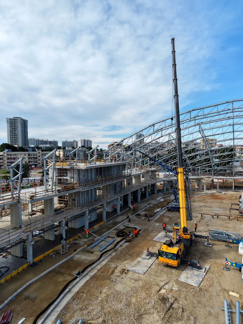 Grove all-terrain crane lifting a prefabricated tubular roof section at the PalaRicciardi arena site