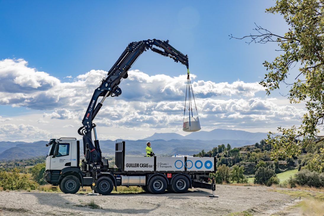 HIAB iQ.708 HIPRO loader crane on a four-axle truck lifting a big bag on a hillside