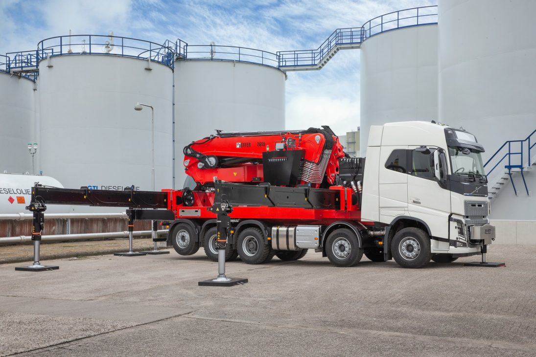 Heavy Hiab loader crane folded on a four-axle truck chassis with stabiliser legs deployed