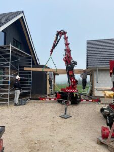 Hoeflon C6e compact crane lifting a timber roof beam into place