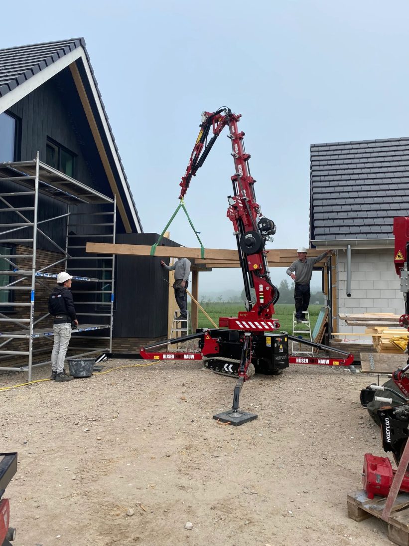 Hoeflon C6e compact crane lifting a timber roof beam into place