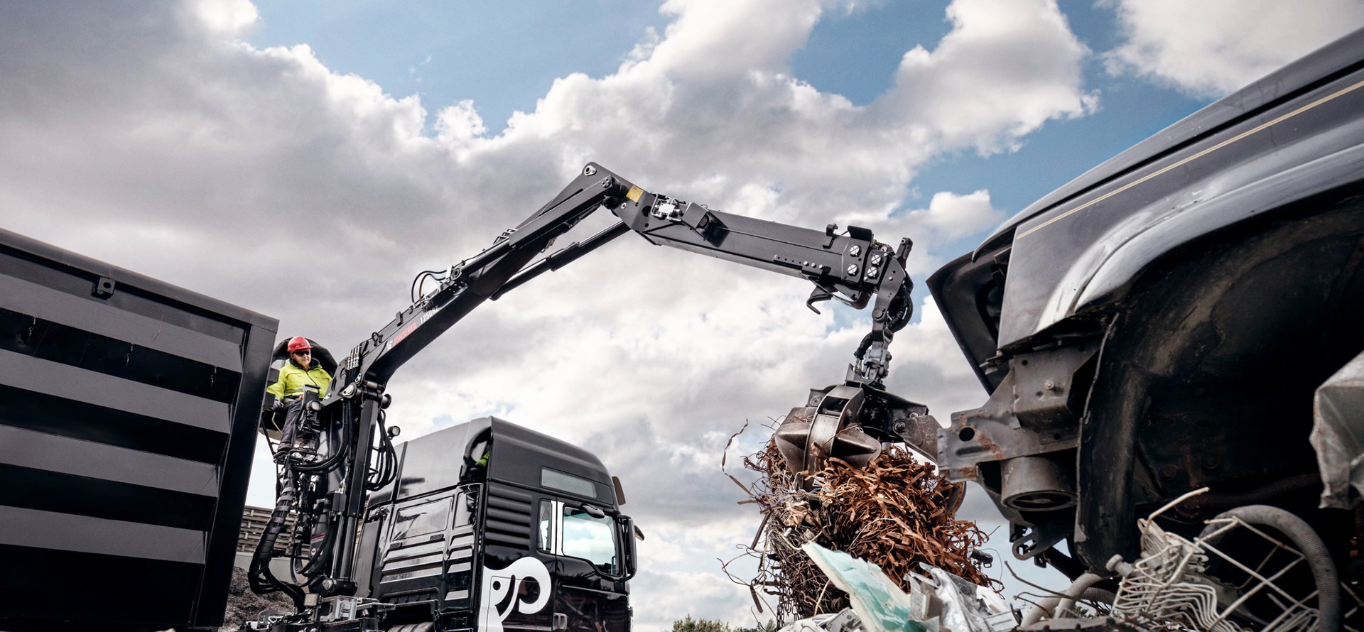 JONSERED recycling crane with grapple loading scrap metal into a truck body