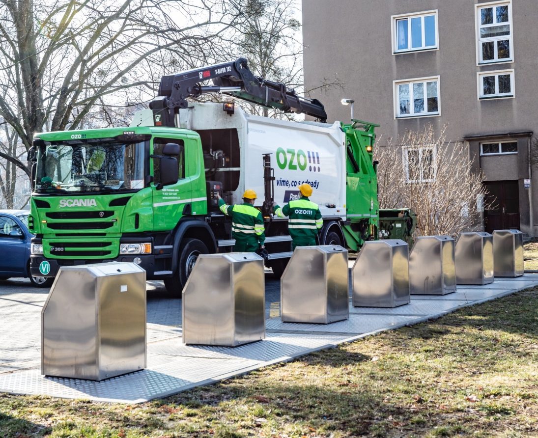 Truck-mounted Hiab crane emptying underground waste containers in a residential street