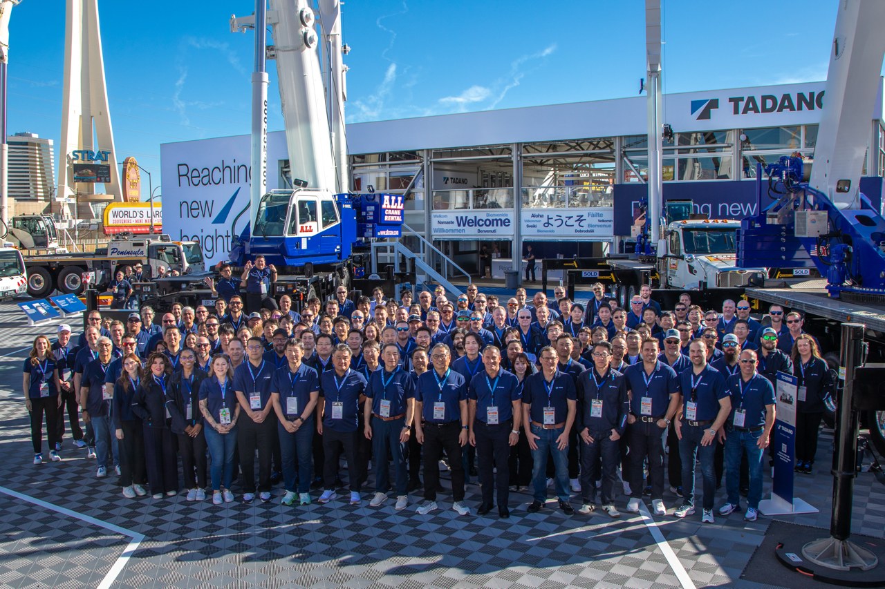 Tadano team gathered in front of the company's CONEXPO-CON/AGG 2026 stand in Las Vegas with rough terrain and boom truck cranes behind them