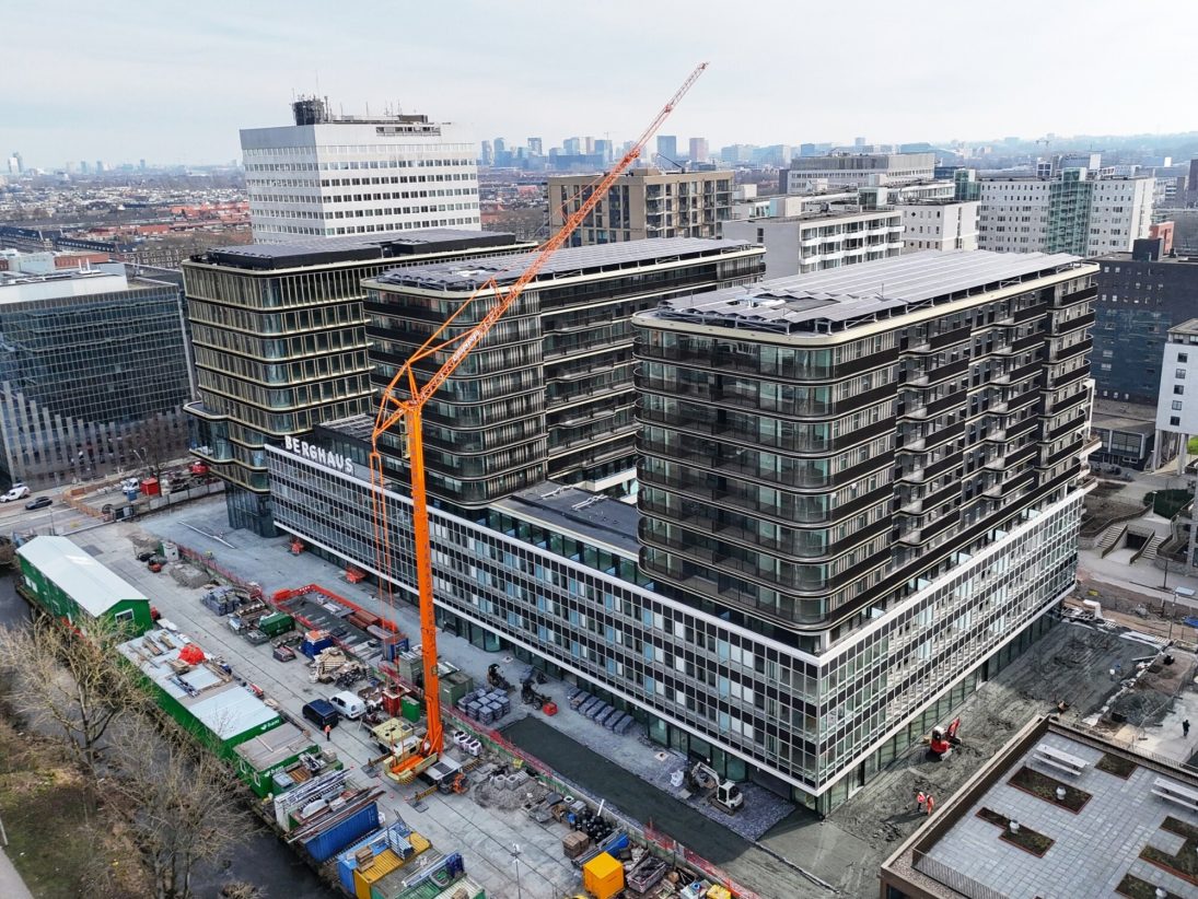 Orange Spierings SK1265-AT6 mobile tower crane rigged beside a city apartment development