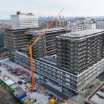 Orange Spierings SK1265-AT6 mobile tower crane rigged beside a city apartment development