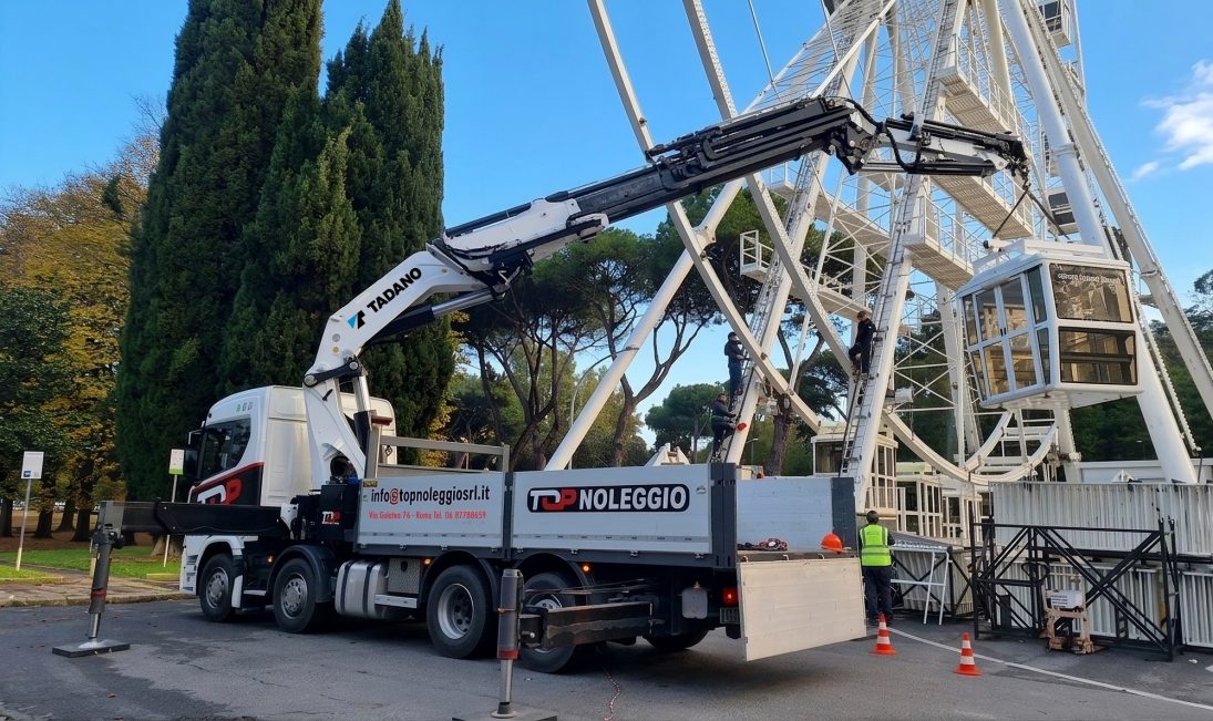 Tadano PM Series knuckle boom crane on a Top Noleggio truck working alongside a Ferris wheel under assembly