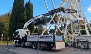 Tadano PM Series knuckle boom crane on a Top Noleggio truck working alongside a Ferris wheel under assembly