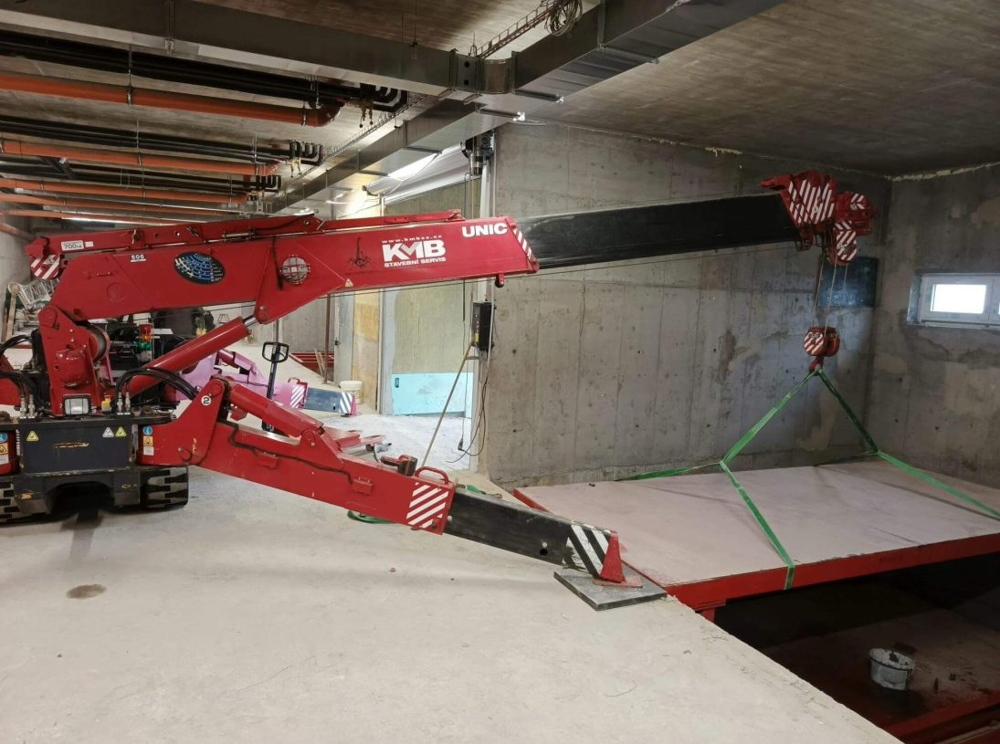 UNIC-506 spider crane lifting inside a low-headroom underground car park in Prague