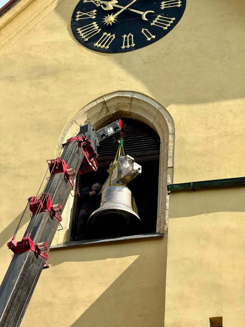 UNIC URW-706 spider crane lifting a bell towards the tower of St James' Church in Hostivice