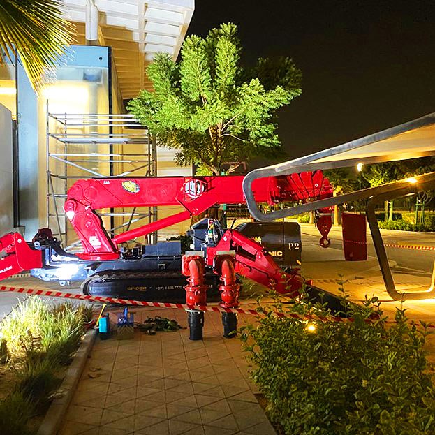 UNIC URW-706 spider crane working at night on the glass façade of Zayed University in Abu Dhabi