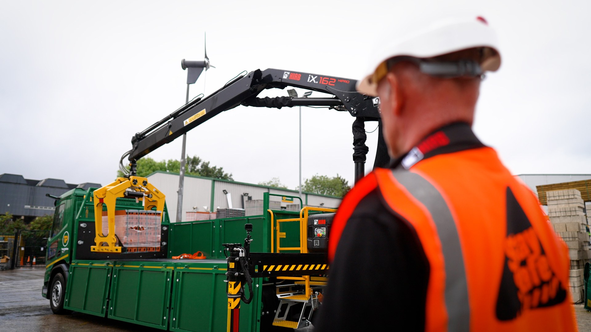 HIAB iX.162 HiPro loader crane handling a pallet of bricks at a builders merchant yard