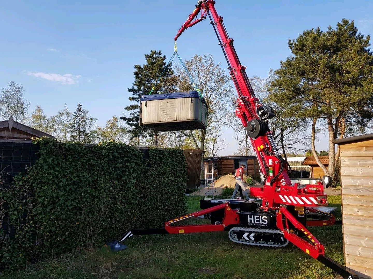 Hoeflon C6 spider crane lifting a jacuzzi over a building