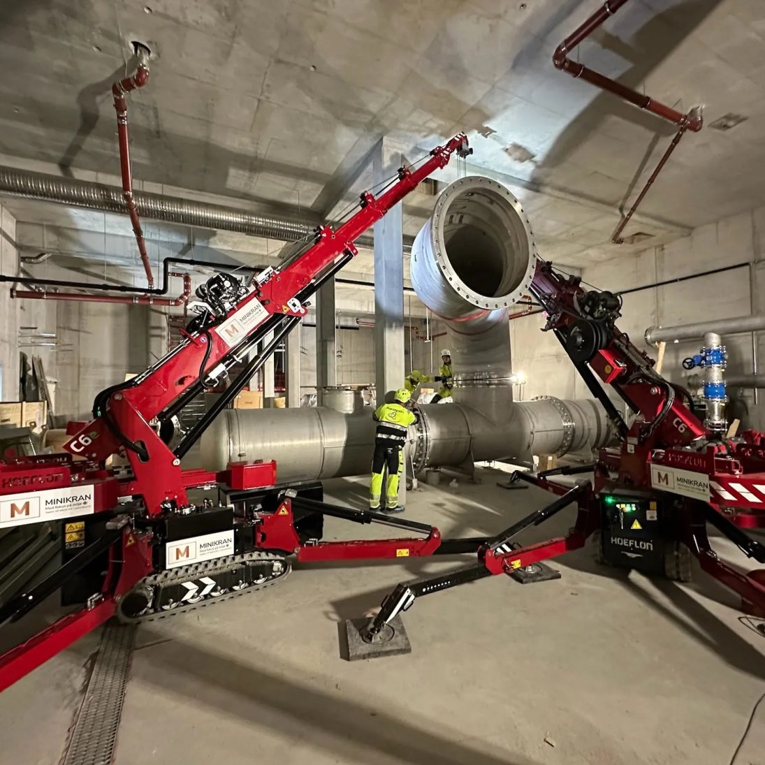 Two Hoeflon mini cranes lifting a pipe in tandem