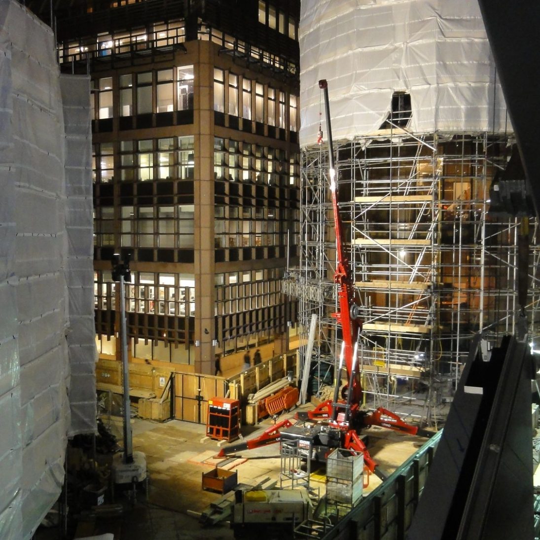 UNIC URW-1006 spider crane working between buildings on the Broadgate site in London at night