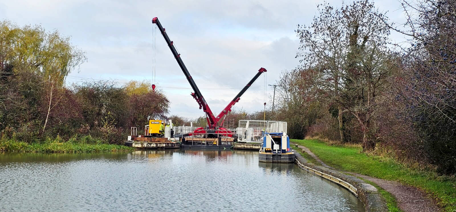 The two Unic URW-706 spider cranes with booms raised either side of the canal lock