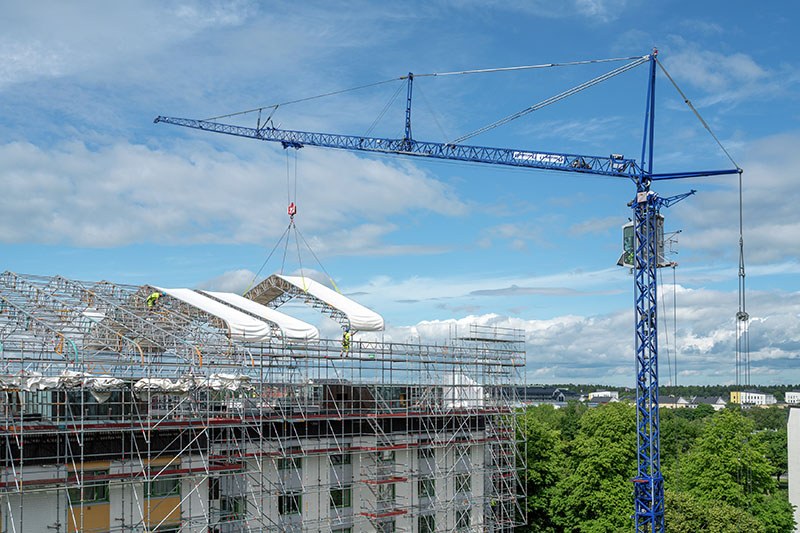 Liebherr MK 88-4.1E mobile construction crane lifting canopy sections between residential blocks in Uppsala