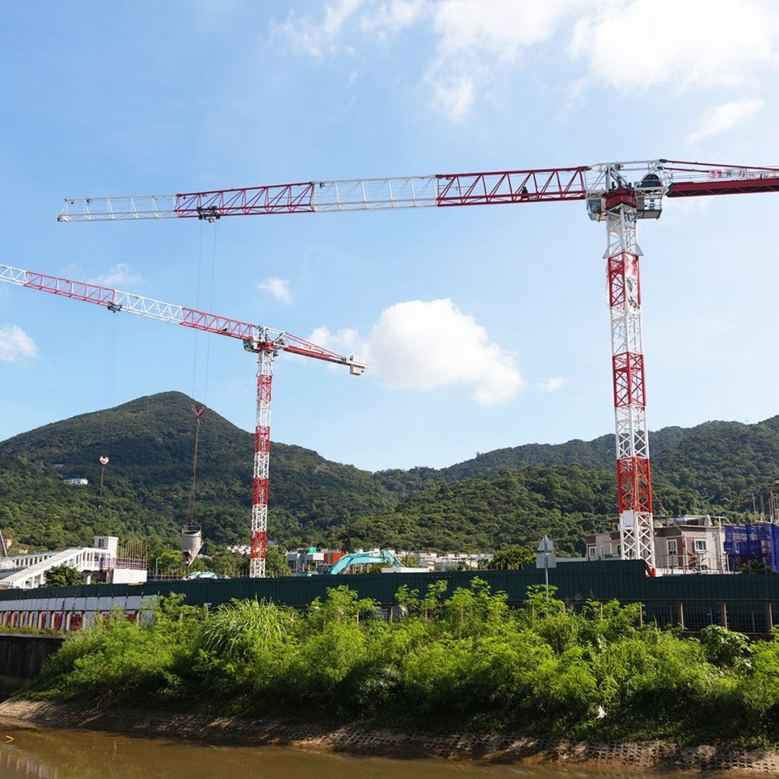 Two Liebherr NC-B 12-70 tower cranes lifting materials at the confined Ho Chung jobsite in Sai Kung