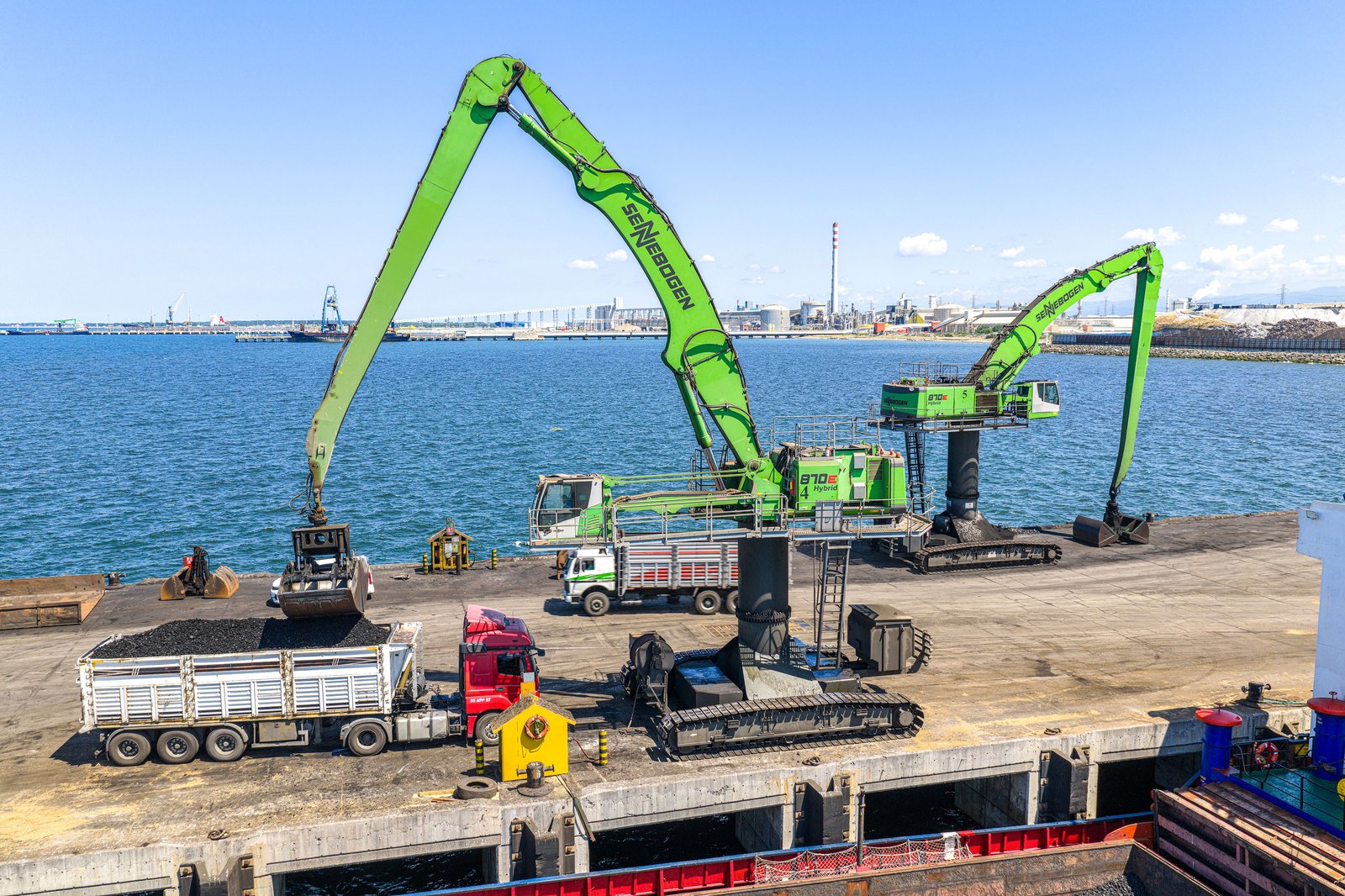 Sennebogen material handlers with grabs loading trucks with bulk material at Yesilyurt port
