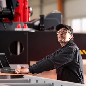 Service technician with laptop beside a Hiab loader crane in a workshop, illustrating ProCare lifecycle services
