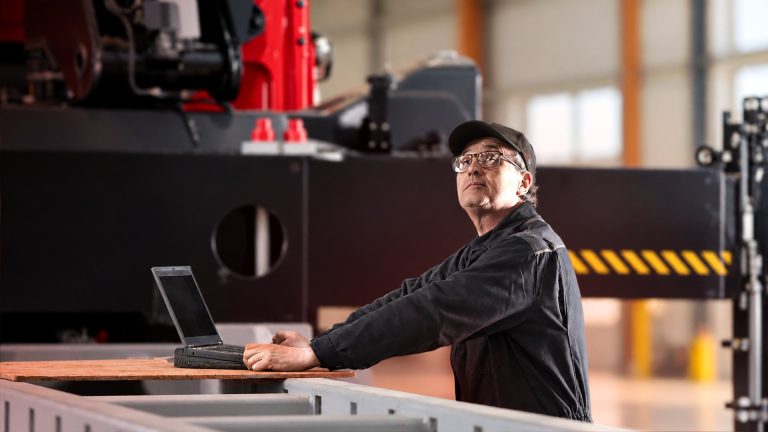 Service technician with laptop beside a Hiab loader crane in a workshop, illustrating ProCare lifecycle services