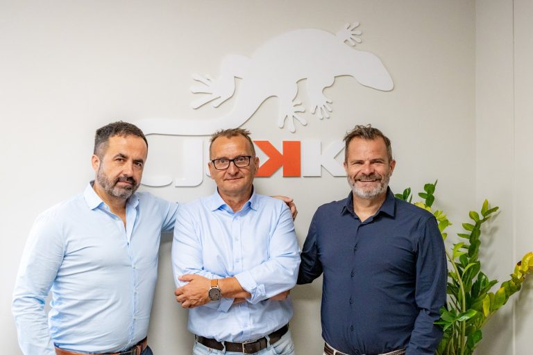 HEWEA and Jekko representatives in front of the Jekko gecko logo at the company's headquarters