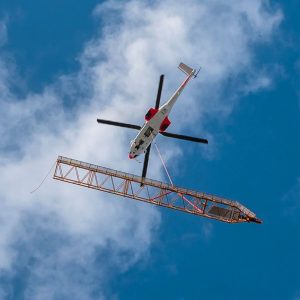 Airbus H225 Super Puma helicopter flying Liebherr 200 DR 5/10 Litronic derrick crane components onto the roof of the Opus 12 tower in Paris La Defense