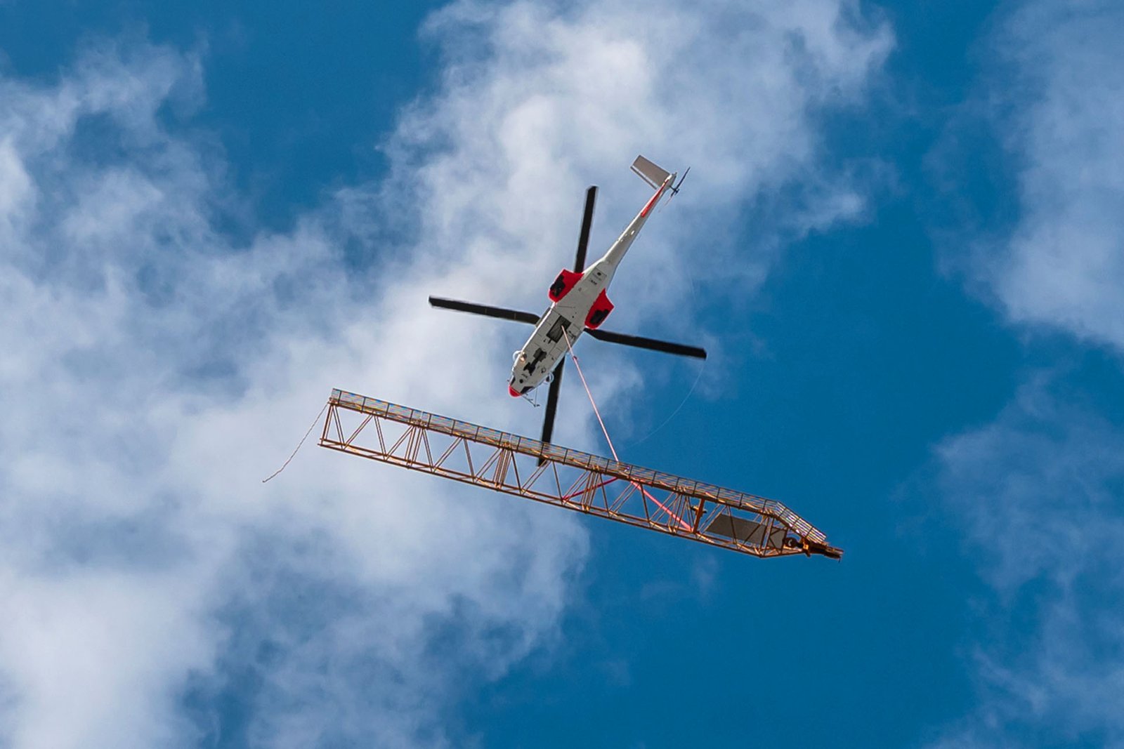Airbus H225 Super Puma helicopter flying Liebherr 200 DR 5/10 Litronic derrick crane components onto the roof of the Opus 12 tower in Paris La Defense