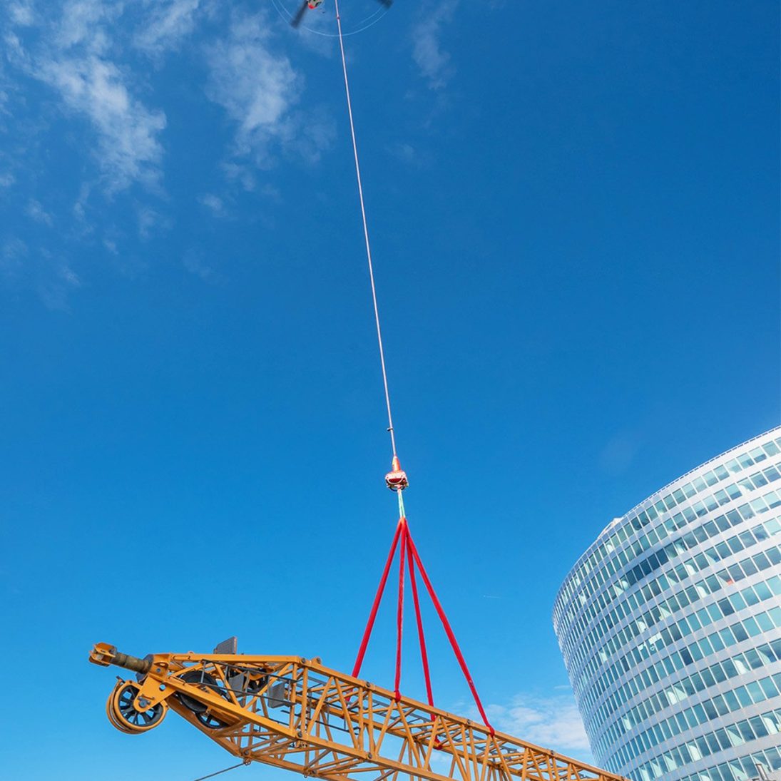Helicopter delivering derrick crane components onto the Opus 12 high-rise roof in Paris
