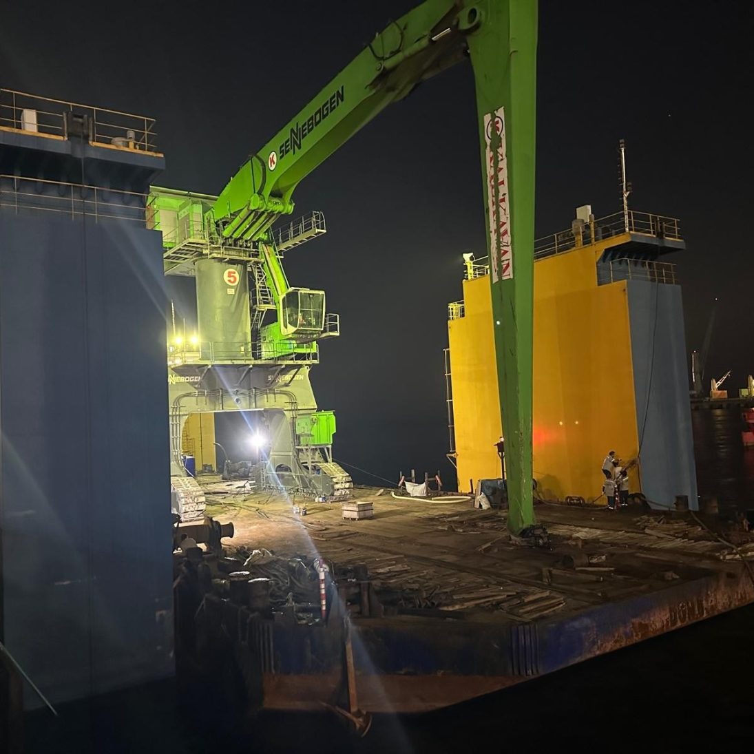 The pontoon carrying the Sennebogen 895 E manoeuvred into the floating dock at night