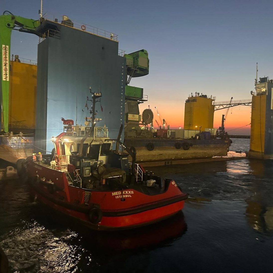 Tugboat positioning the pontoon and floating dock during unloading of the Sennebogen 895 E