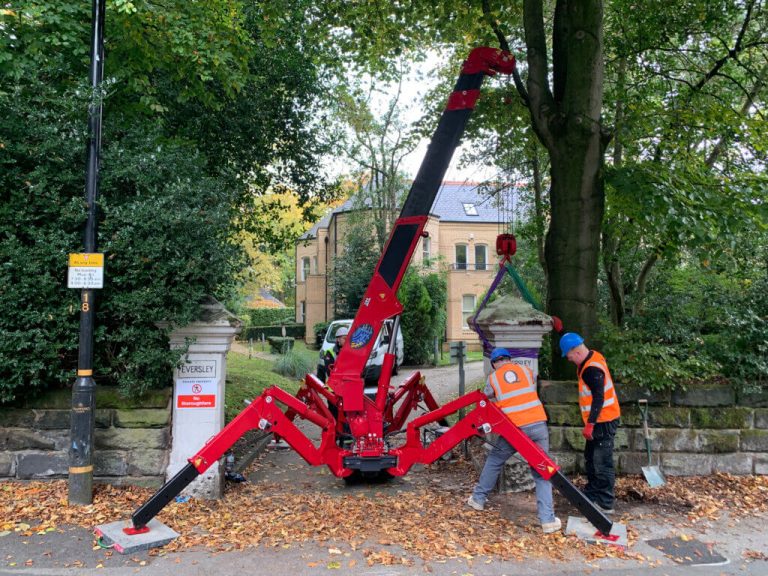 Unic URW-095 mini spider crane lifting a stone pillar cap through a narrow gateway